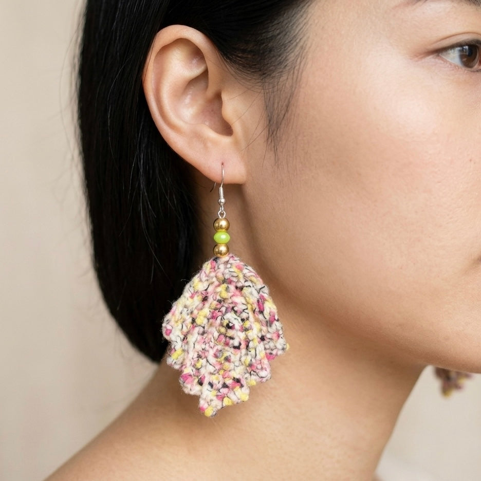 Close-up of a colorful tassel earring on an ear against a neutral background