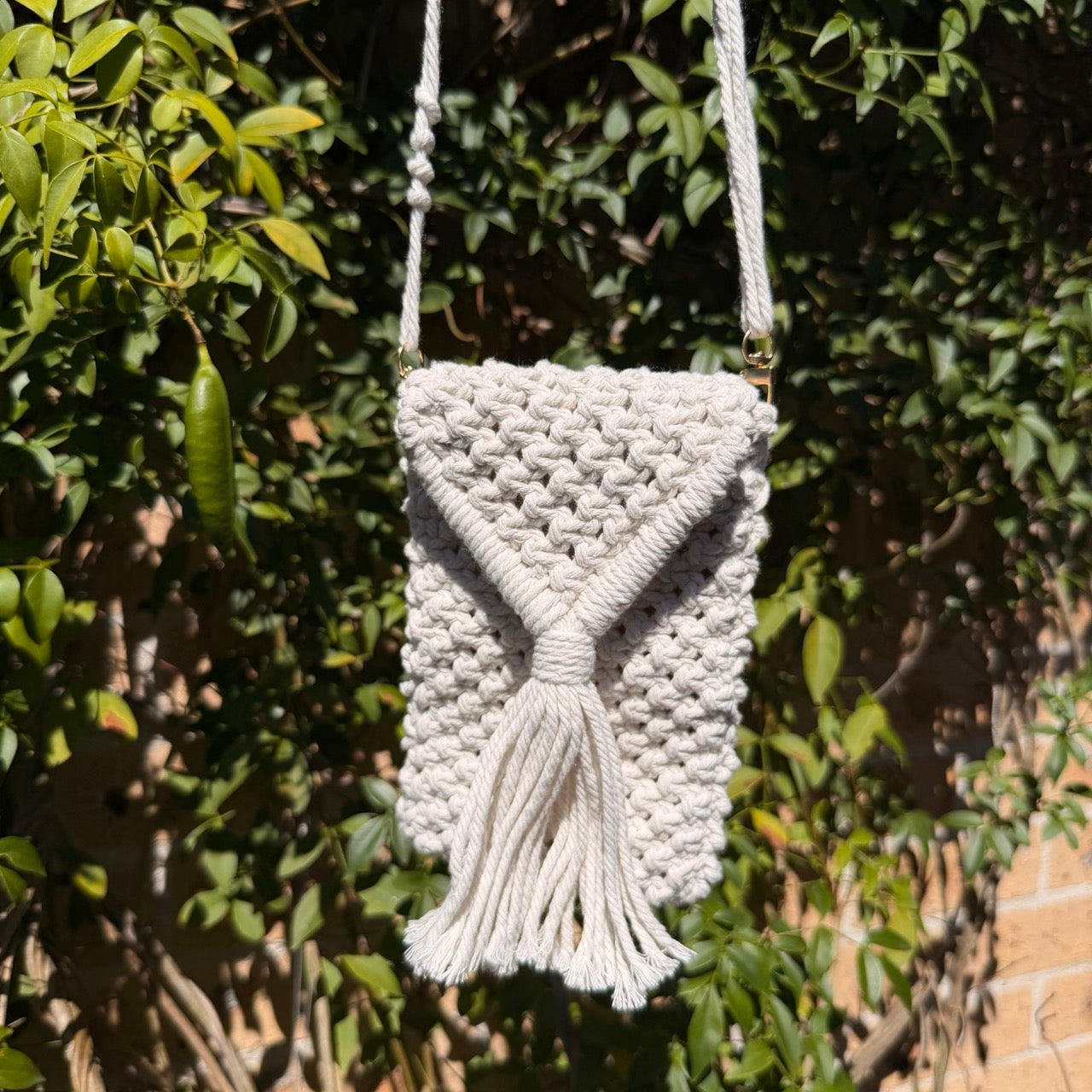 Macrame handbag with tassel hanging from a tree